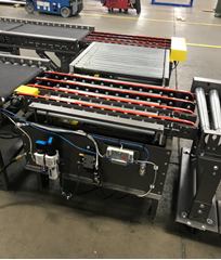 The box and tray transfer conveyor allows for line to line product transfer in a smaller footprint compared to bulky radius curve conveyors